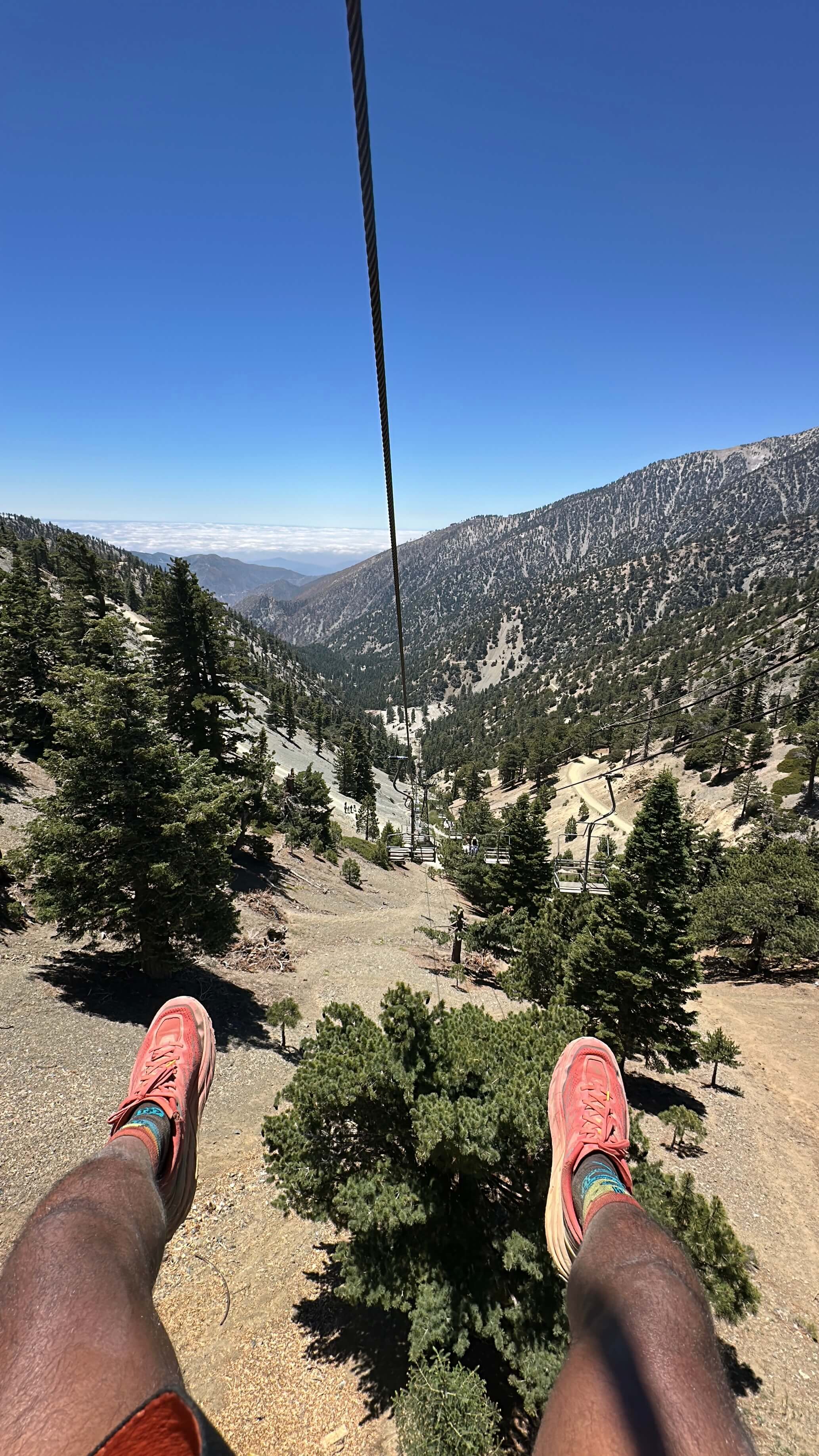 Feet up on the ski lift ride down, looking out over the ridge and cloud layer